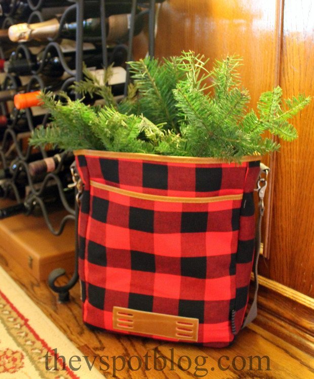 red and black buffalo check bag filled with fresh greenery for Christmas